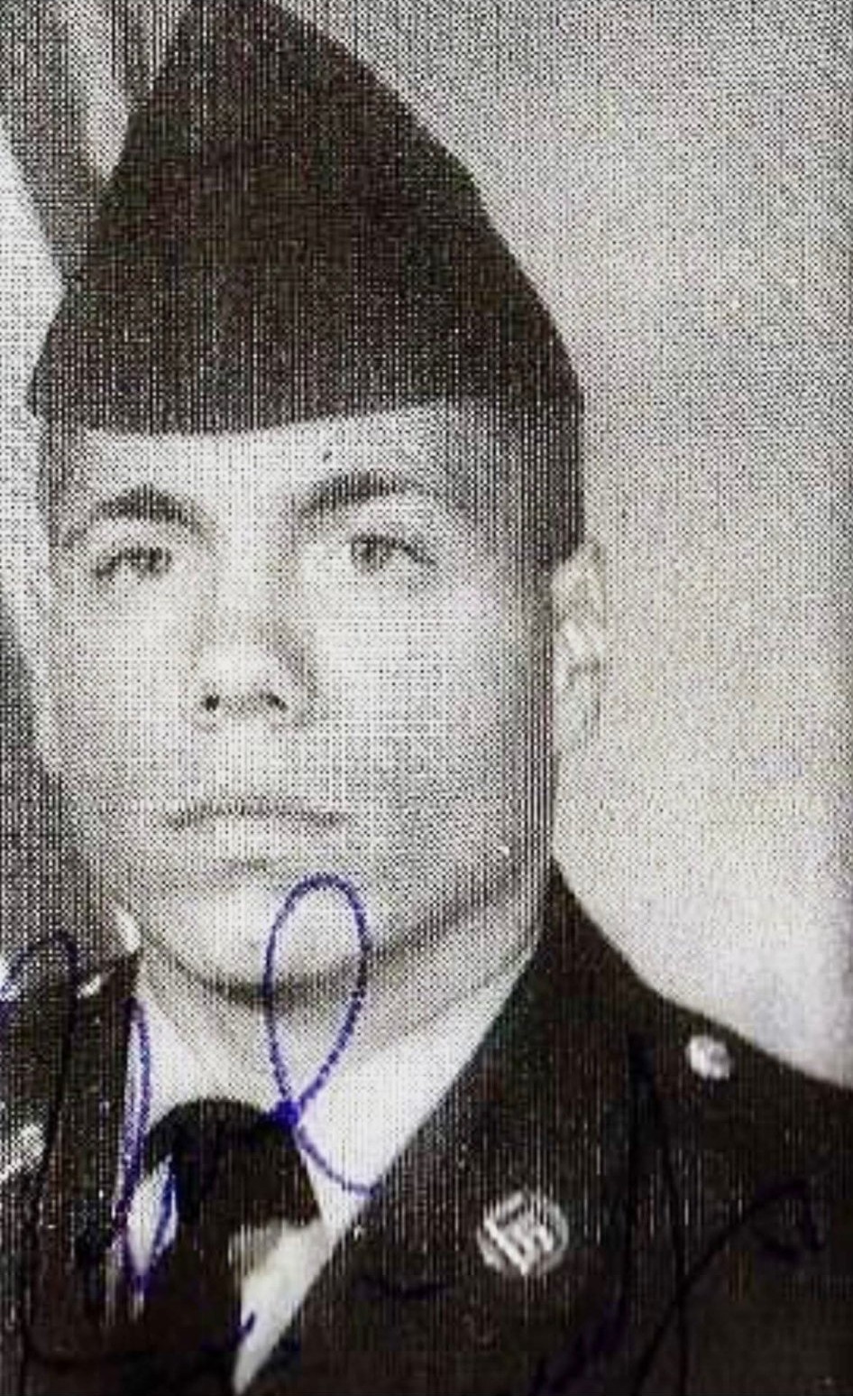 A grainy, ink-marked black-and-white soldier portrait before restoration