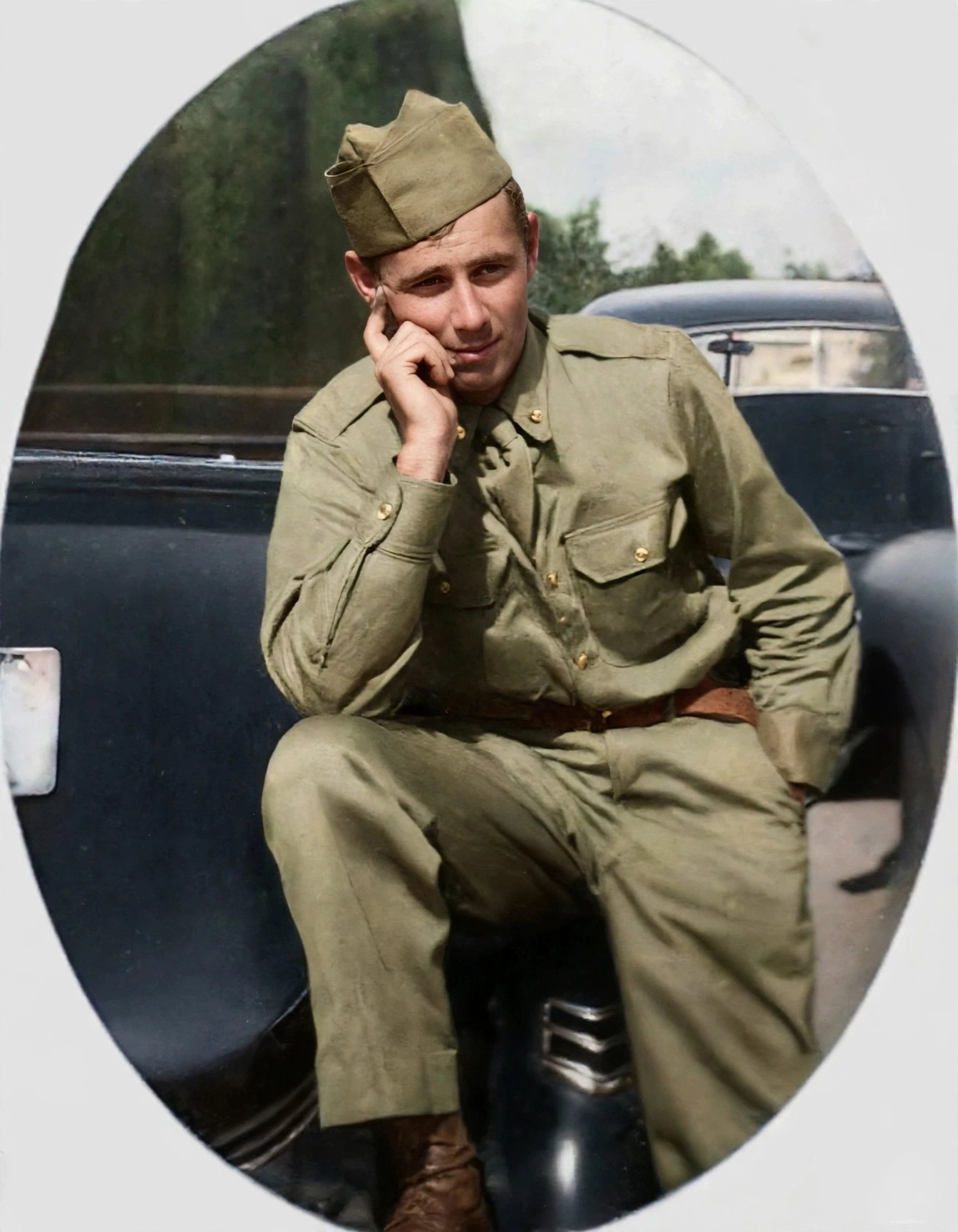 The oval soldier portrait restored and colorized: the soldier in olive uniform sitting on a car, in full natural colour